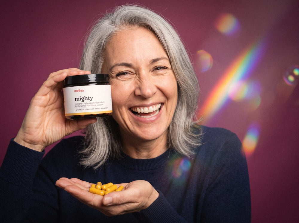 A smiling woman holding a jar of Mighty and her capsules