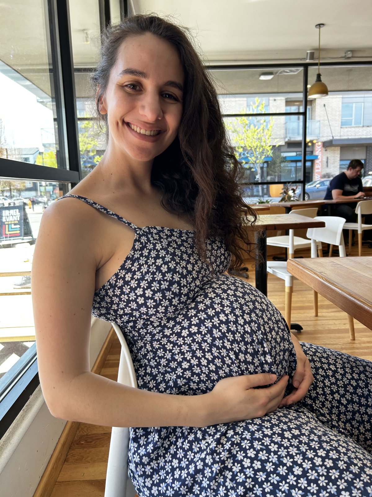 Laila, pregnant, smiling in a café